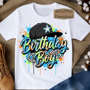May include: White t-shirt featuring a colorful graphic design. The design includes a black baseball cap with a white star, the words "Birthday Boy" in blue and orange, and a skateboard with a checkered pattern. The shirt also has paint splatter details.