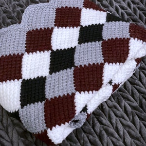 May include: A crocheted blanket with a checkered pattern in burgundy, white, black, and gray.