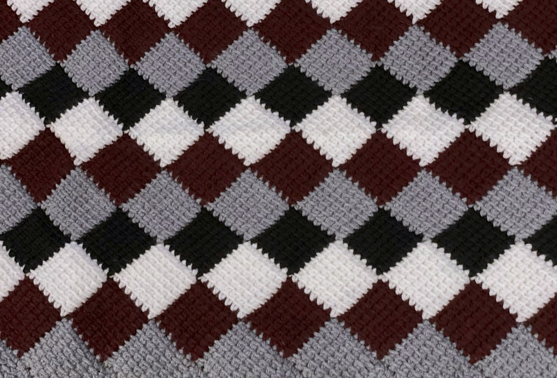 May include: A crocheted blanket with a diamond pattern in shades of burgundy, gray, black, and white.