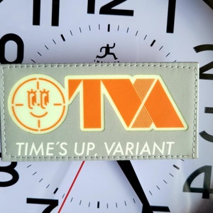 May include: A gray patch with a white target symbol, a stylized orange "M" and the text "TIME'S UP, VARIANT".