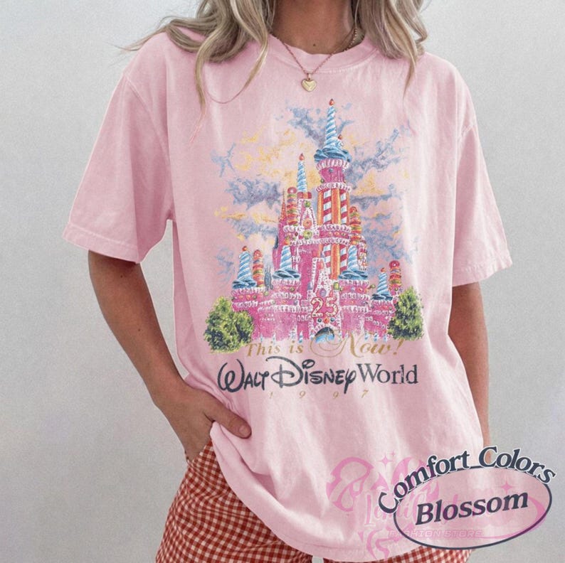 Op de afbeelding: Lichtroze T-shirt met een afbeelding van het kasteel van Assepoester en de tekst "This is Now! Walt Disney World 1997". Het shirt is van Comfort Colors Blossom.