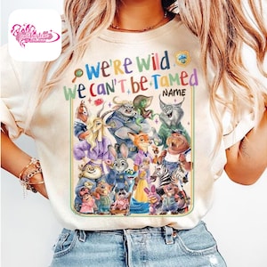 Puede incluir: Camiseta color crema con un gr&aacute;fico colorido de personajes de Zootopia. El texto "We're Wild, We Can't Be Tamed" est&aacute; encima de los personajes. Una peque&ntilde;a insignia est&aacute; en la esquina superior derecha. La camiseta es de cuello redondo.