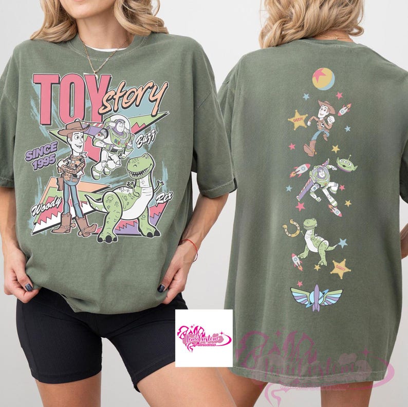 May include: Olive green t-shirt featuring the words "TOY STORY" in pink and white, with Woody, Buzz, and Rex graphics. The back of the shirt has additional character graphics. The text "SINCE 1995" is also visible.