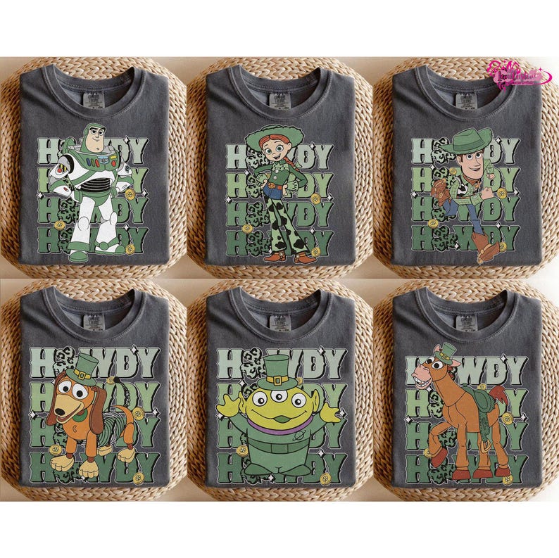 May include: Six gray t-shirts featuring characters from the Toy Story franchise. Each shirt has a different character with the word "Howdy" in a green and white design. Characters include Buzz Lightyear, Jessie, Woody, Slinky Dog, an alien, and Bullseye.