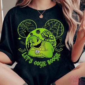 May include: Black t-shirt with a green graphic of Oogie Boogie from The Nightmare Before Christmas. The design includes bats, spiderwebs, and the text "Let's Oogie Boogie" in green. The shirt has a round neckline.