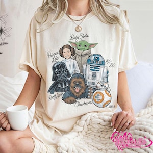 May include: A white ceramic mug with a black handle and the text "But First, Coffee" in a bold, black font. The mug is set against a blurred background, suggesting a cozy setting.