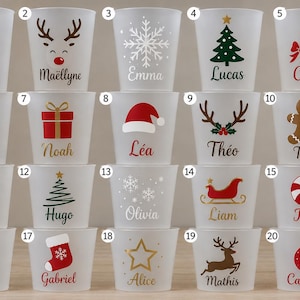 Peut inclure: Un ensemble de vingt gobelets en plastique givré, chacun orné d'un motif de Noël unique et d'un prénom personnalisé imprimé en différentes couleurs et polices, incluant des icônes comme le Père Noël, des rennes, des flocons et des sapins.