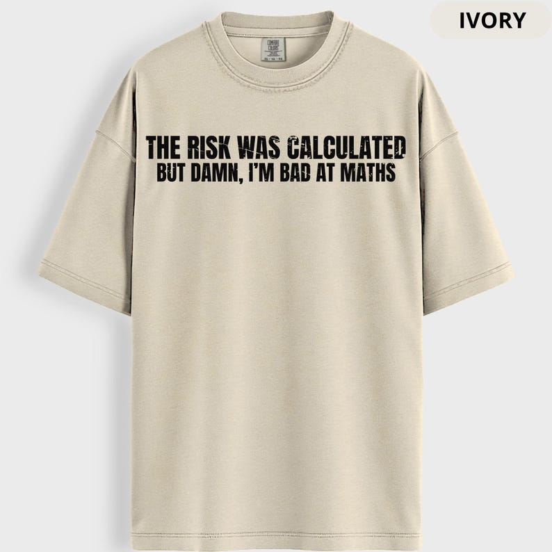 Peut inclure: T-shirt ivoire avec l'inscription noire "THE RISK WAS CALCULATED BUT DAMN, I'M BAD AT MATHS". Le t-shirt a un col rond et des manches courtes. Le t-shirt est de couleur neutre.