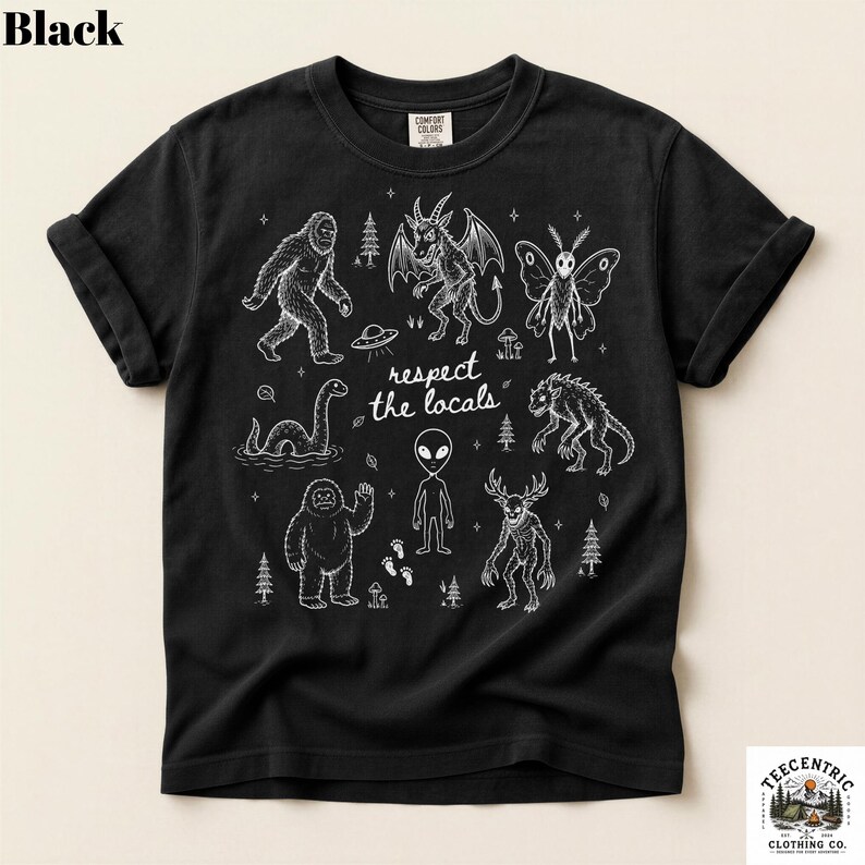 May include: A black short-sleeve t-shirt featuring a white graphic print of various cryptids and extraterrestrial figures, including Bigfoot, an alien, and a mothman. The text "respect the locals" is centered among the illustrations.