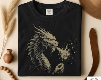 May include: Black crew neck t-shirt with a gold dragon graphic. The dragon is exhaling a dandelion puff, with the text "Comfort Colors" on the label. The shirt is from Teecentric Clothing Co.