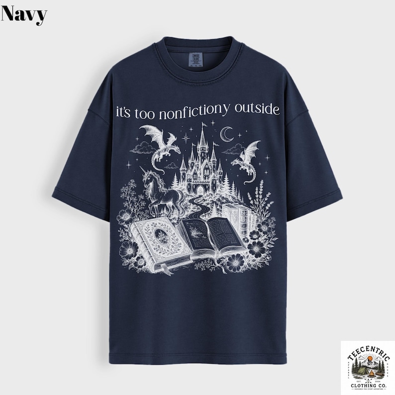 May include: Navy blue t-shirt with a white graphic featuring a castle, dragons, a unicorn, and open books. The text "it's too nonfictiony outside" is printed above the graphic. The shirt has short sleeves and a crew neck.
