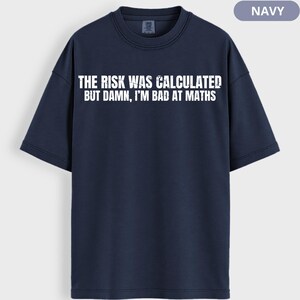 Peut inclure: T-shirt bleu marine avec l'inscription blanche "THE RISK WAS CALCULATED BUT DAMN, I'M BAD AT MATHS". Le t-shirt &agrave; manches courtes a un col rond. Le v&ecirc;tement est de couleur bleu marine uni.