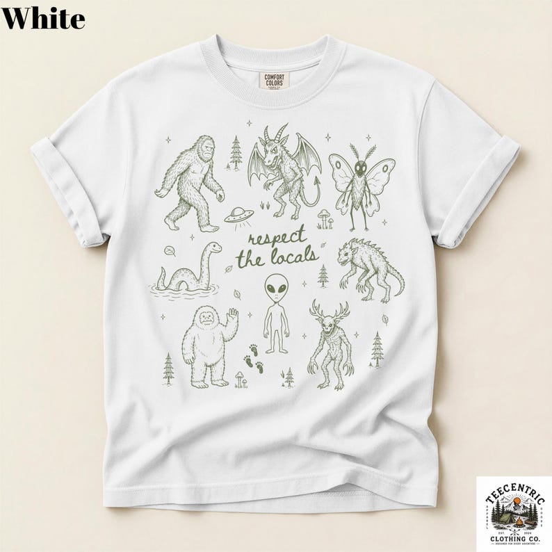 May include: A white short-sleeve t-shirt featuring a dark green line art graphic of various cryptids and the text "respect the locals" in the center. The design includes illustrations of Bigfoot, a mothman, an alien, and other creatures.