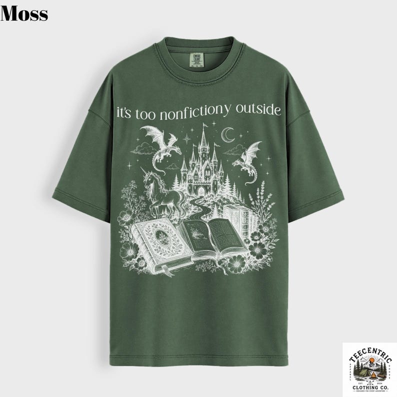 May include: Moss green t-shirt with the text "it's too nonfictiony outside" above a fantasy graphic. The graphic features a castle, dragons, a unicorn, and open books. The shirt has short sleeves and a crew neck.