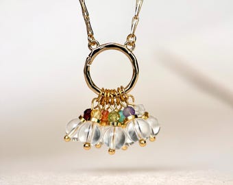 May include: A gold chain necklace featuring a circular pendant charm. The pendant is adorned with a cluster of small, dangling clear spherical beads and tiny multi-coloured faceted gemstone beads in shades of red, orange, yellow, green, and purple.