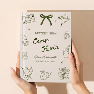 May include: A personalized journal titled "Letters From Camp Olivia" with a cream-colored cover. The cover features green illustrations of camping-themed icons and text. The text includes "Olivia's Bachelorette" and the date "December 15, 2025".