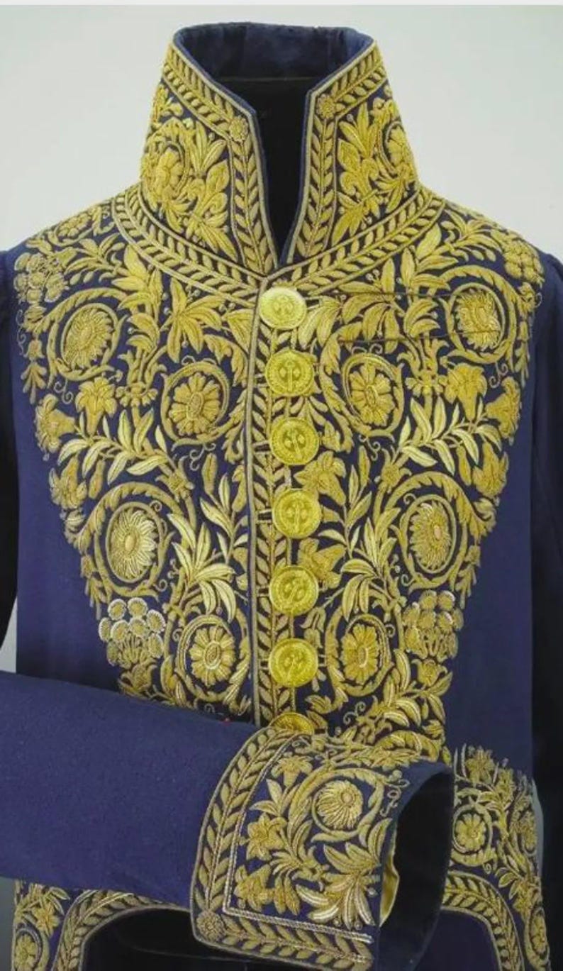 May include: A navy blue jacket with intricate gold embroidery. The jacket features a high collar, gold buttons, and ornate floral and leaf patterns. The sleeve cuffs also have gold embroidery.