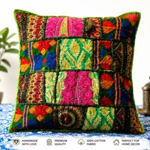 Puede incluir: Cojín decorativo cuadrado con diseño de patchwork. El cojín presenta una vibrante mezcla de colores que incluyen verde, rosa, rojo y azul, con intrincados patrones bordados. Los bordes están ribeteados con un borde verde. El texto en la parte inferior dice "HANDMADE WITH LOVE", "PREMIUM QUALITY", "100% COTTON FABRIC" y "PERFECT FOR HOME DECOR".