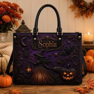 May include: A rectangular purple handbag featuring a black handle and a relief design of a witch holding a lantern, a jack-o'-lantern, a crescent moon, stars, and bats. The name Sophia is printed in gold lettering on a central decorative plaque.