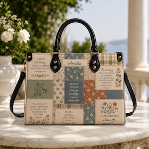 May include: A rectangular handbag with black leather handles and a patchwork-style exterior featuring floral patterns, plaid sections, and printed Bible verses. The name Amelia is centered at the top, with black hardware accents throughout.
