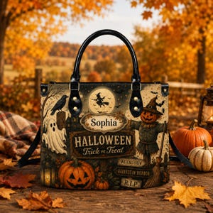 May include: A black-handled handbag featuring a Halloween scene with a ghost, a jack-o'-lantern, a scarecrow, and a witch on a broomstick. The bag displays the name Sophia, the text Halloween Trick or Treat, Witches Brew, Harvest of Horror, and R.I.P.