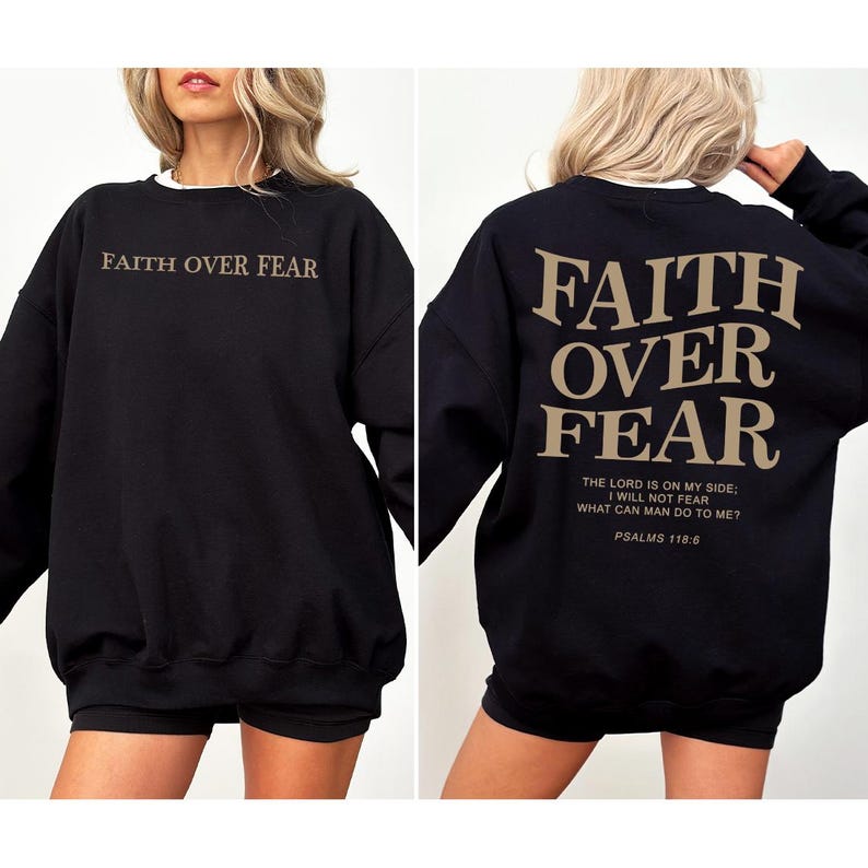 May include: Black sweatshirt with the text "FAITH OVER FEAR" in a tan color on the front and back. The back also includes the Bible verse Psalms 118:6. The sweatshirt has a white collar.