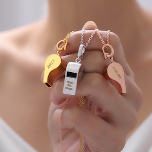 May include: Three pendant necklaces featuring whistle charms in gold, silver, and rose gold. The gold whistle has "2025" engraved. The silver whistle has "Team San Diego" engraved. The rose gold whistle has "11.09.1997" engraved.