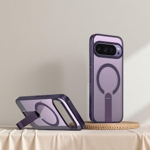 May include: Two purple phone cases with a stand feature. One case is upright, showcasing the camera and a circular design. The other case is angled, with the stand extended. The cases are on a neutral background.