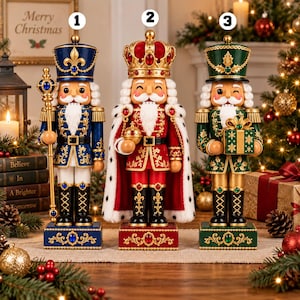 May include: Three decorative nutcracker figurines standing in a row. The first is blue with a gold scepter, the second is a red king with a crown and cape, and the third is green holding a gift box. Each stands on a rectangular base.