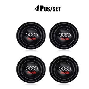 May include: A set of four circular black car wheel center caps featuring the white Audi four-ring logo and the red Audi text. The text 4Pcs/SET is displayed above the four identical circular emblems, which have a glossy finish and a raised border.