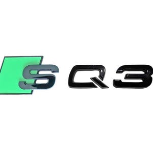 May include: Black and green "S Q3" emblem. The "S" is black with a green background. The "Q3" is in a bold, black font. The emblem is likely for a car.