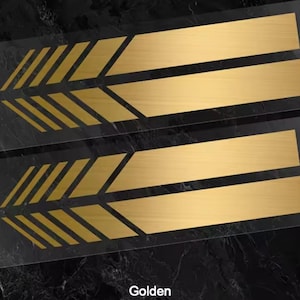 Pode incluir: Dois autocolantes retangulares idênticos com um acabamento dourado metálico. Cada autocolante apresenta uma série de riscas diagonais paralelas no lado esquerdo que transitam para duas barras horizontais longas e sólidas à direita.