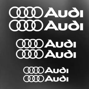 Może przedstawiać: Białe naklejki z logo Audi na czarnym tle. Naklejki przedstawiają pierścienie Audi i nazwę marki pogrubioną, bezszeryfową czcionką. Obraz przedstawia wiele naklejek, idealnych dla entuzjastów motoryzacji.