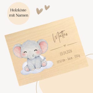 May include: A wooden plaque with a cartoon elephant on a cloud. The plaque has the name "Matteo", a date, time, length of 56cm, and weight of 3350g. The text "Holzkiste mit Namen" is in a circle in the upper left corner.