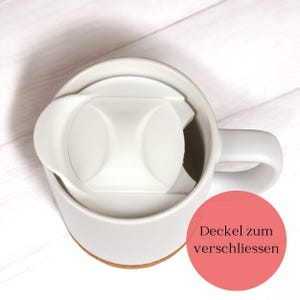 May include: A white ceramic mug with a matching lid. The lid is designed to fit snugly inside the mug, with a small opening for drinking. The mug sits on a light brown coaster. The image includes the text "Deckel zum verschliessen".