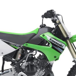 Peut inclure: Une moto tout-terrain Kawasaki KX85 verte et noire. La moto présente un réservoir de carburant, une selle et des carénages verts, avec le logo Kawasaki. Le cadre est noir et les pneus sont visibles.