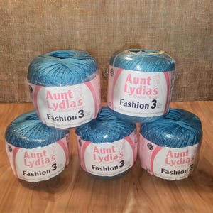 May include: Five spools of Aunt Lydia's Fashion 3 crochet thread in a vibrant teal color. Each spool is wrapped in clear plastic with a pink and white label. The labels display the brand name and product details.