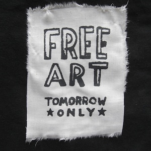 May include: White fabric patch with black text that reads "FREE ART TOMORROW ONLY" with a star on either side of the word "ONLY".