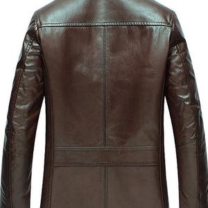 May include: A brown leather jacket with a classic design. The jacket features a collared neckline, long sleeves, and a tailored fit. The back of the jacket has a horizontal seam across the upper back and a vertical seam down the center.