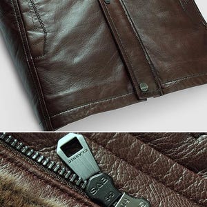 May include: Close-up of a brown leather jacket. The jacket features a zipper with the word "CLASSIC" on the pull tab. The leather has a textured appearance, and the jacket has a buttoned closure.
