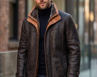 May include: A brown leather jacket with a shearling collar and cuffs. The jacket has a button-up front, two side pockets, and a dark brown exterior. The collar and trim are a lighter shade of brown. The person is wearing a black turtleneck and blue jeans.