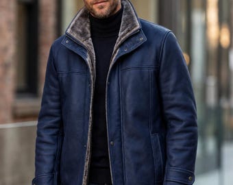 May include: A navy blue jacket with a high collar, featuring a grey faux fur lining, a front zipper closure, and snap button details. The jacket has long sleeves with adjustable cuffs and vertical seam detailing on the front panels.
