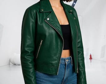 May include: A dark green leather jacket with a classic biker style, featuring a notched collar, asymmetrical zipper, and multiple pockets. The jacket is paired with a black top and blue jeans.