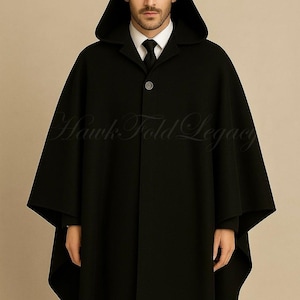 May include: A black hooded cape with a single-button fastening. The cape has a tailored design and a hood that drapes over the shoulders. The text "Hawk Fold Legacy" is visible on the cape.