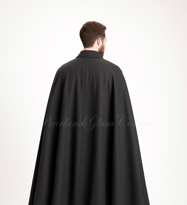 Puede incluir: Una capa de lana gris carb&oacute;n hasta el suelo con un cuello estructurado y un dise&ntilde;o de espalda sin costuras. La prenda cae desde los hombros en una silueta amplia y fluida. El texto Pearland Glam Corner es visible.