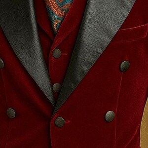 May include: A burgundy velvet tuxedo jacket with black satin lapels and buttons. A patterned scarf in teal and rust tones is visible at the neck. The jacket has a classic, formal design.