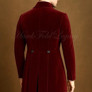 May include: A burgundy velvet coat with a high collar and two black buttons at the waist. The coat has a long, tailored fit and a split back. The text "Hawk Fold Legacy" is visible in the image.