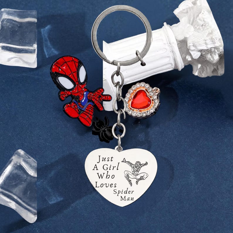Puede incluir: Un llavero plateado con un dije de Spider-Man rojo y azul, un dije de ara&ntilde;a negra y un dije en forma de coraz&oacute;n con el texto "Just A Girl Who Loves Spider-Man". Tambi&eacute;n incluye un dije rojo en forma de coraz&oacute;n con borde dorado.