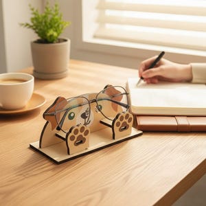May include: A light-coloured wooden eyeglass stand shaped like a dog with brown and white markings. The stand features two raised paw-shaped supports that hold a pair of thin-framed glasses in place, resting on a rectangular base.