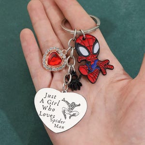 Puede incluir: Llavero con un dije de Spider-Man rojo y negro, un dije en forma de coraz&oacute;n con una gema roja y una etiqueta en forma de coraz&oacute;n con el texto "Just A Girl Who Loves Spider-Man". Incluye un peque&ntilde;o dije de ara&ntilde;a negra.